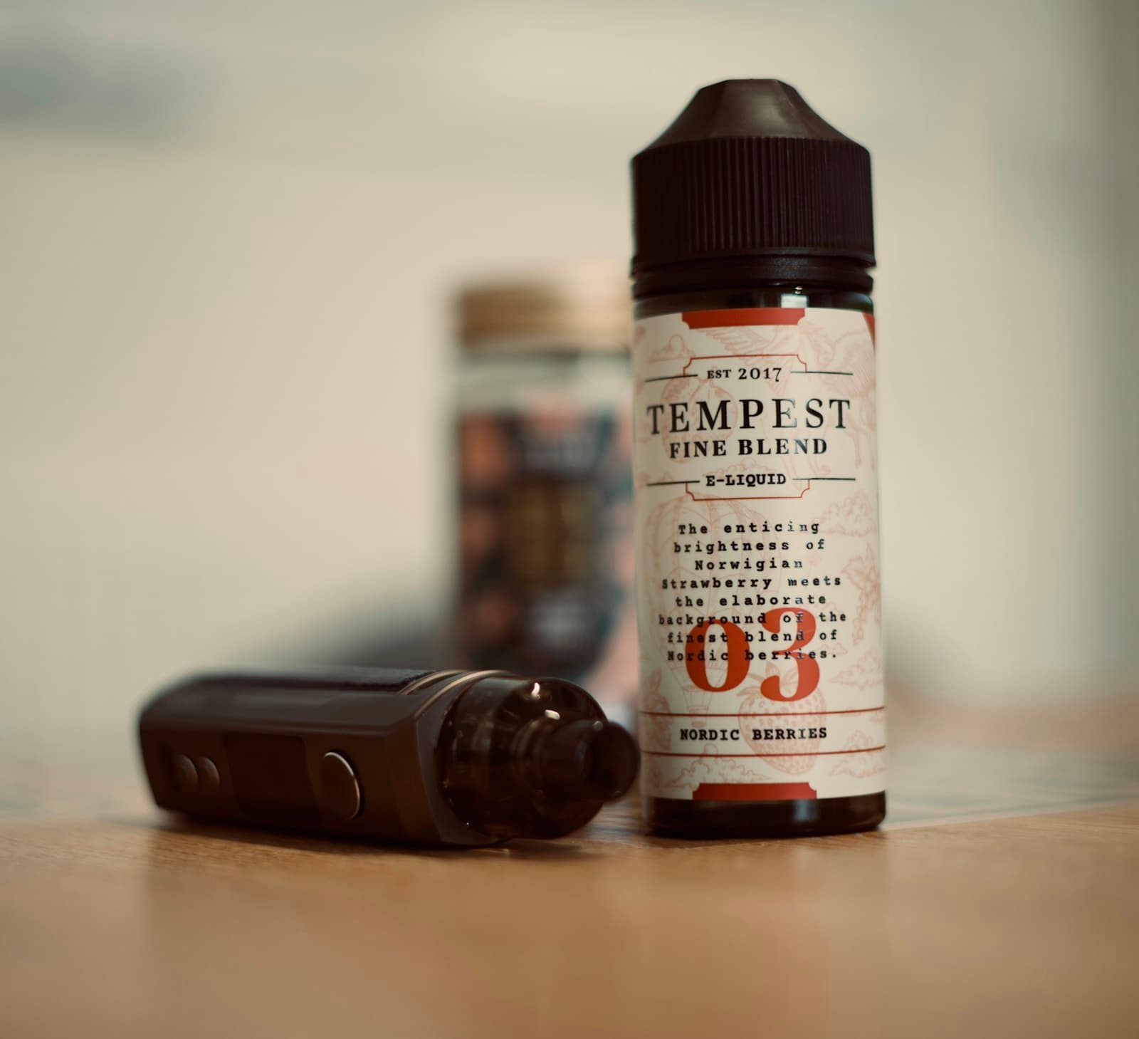 Bottle of e-liquid standing next to a pod mod device on a table
