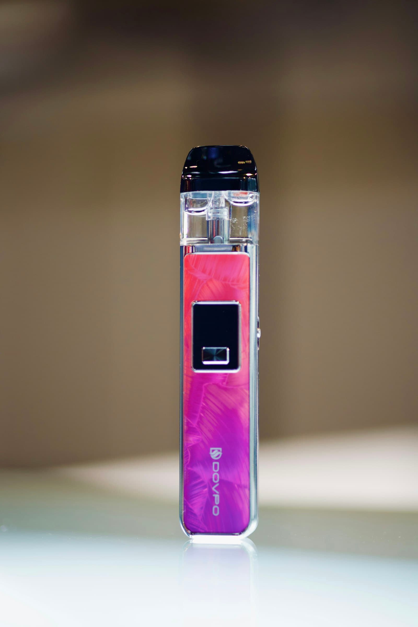 A rechargeable pod vape kit resting on a table with its pod removed