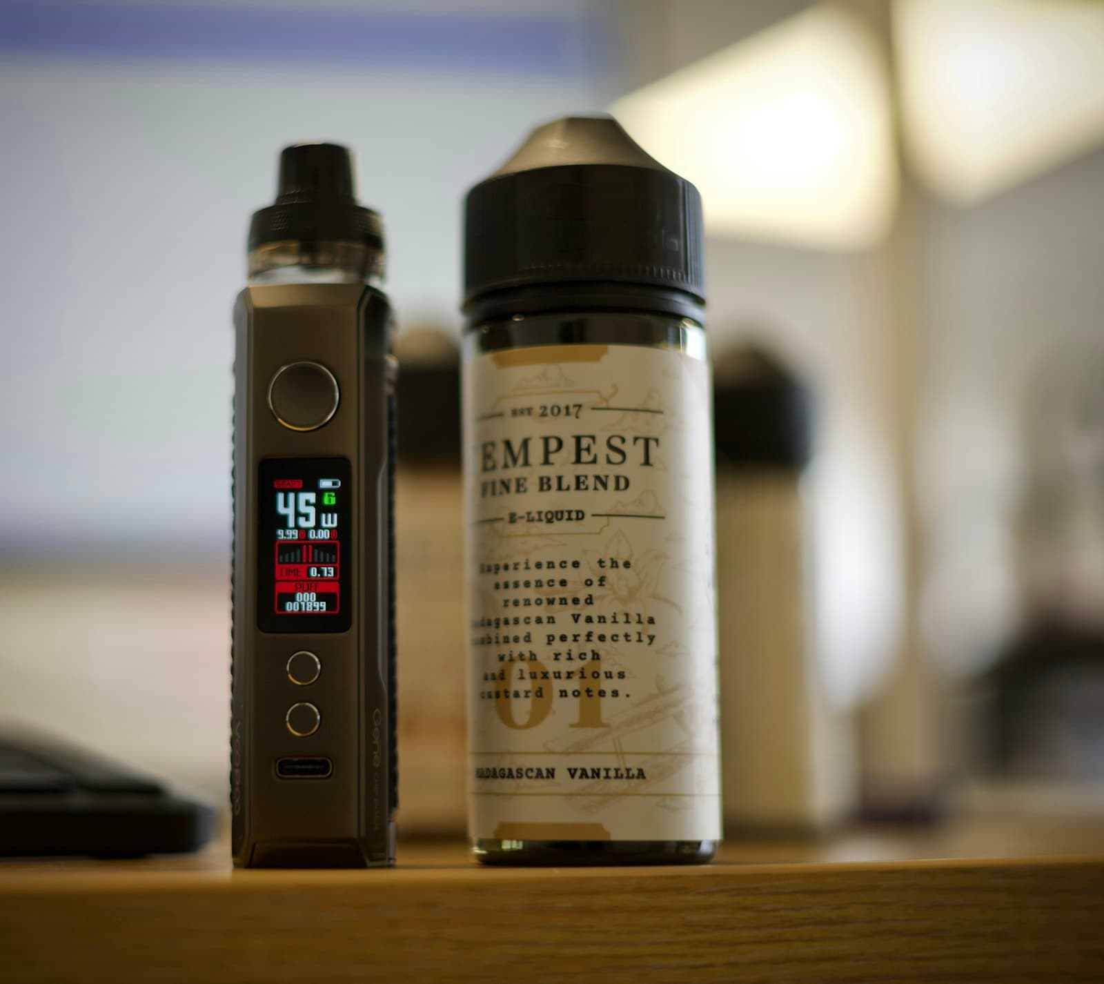 A bottle of nicotine salt e-liquid standing next to a pod vape device on a table