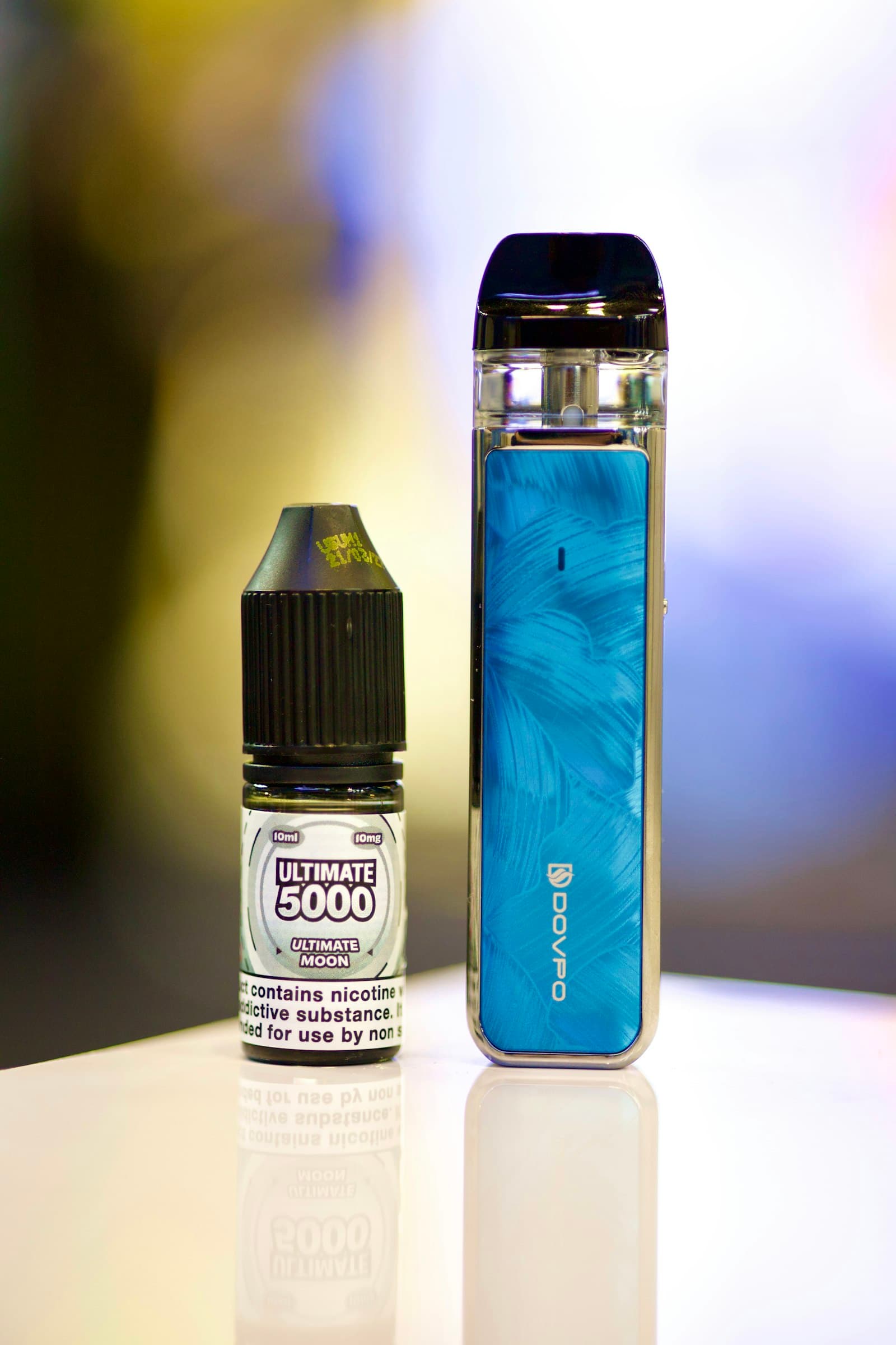 Pod vape kit standing next to its e-liquid bottle on a table