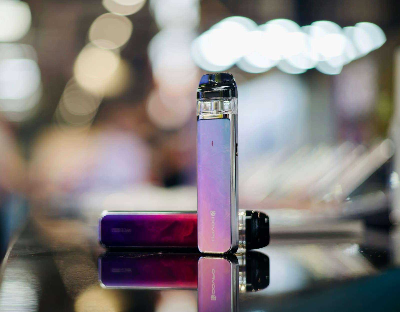 A rechargeable pod vape kit and its pod resting on a wooden table